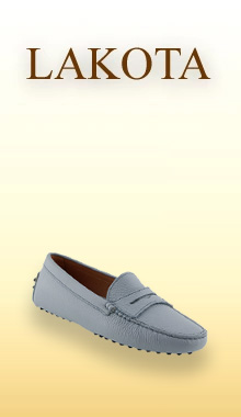 Lakota Mokassin in Hellblau Ein eleganter, hellblauer Mokassin von uns ist vor einem sanften, warmen Farbverlauf im Hintergrund platziert, der an Frühlings- oder Sommertöne erinnert. Der Schuh wirkt leicht und bequem, mit einer schlichten Silhouette, feinen Nähten und einer flexiblen Sohle, die für entspannten Tragekomfort steht.